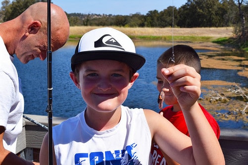 kid holding a fishing line with worm hooked on it