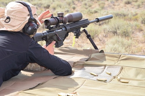 man focusing rifle scope