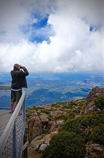 man using binocs to view cliff