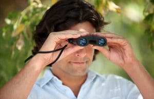 Man looking through compact binoculars