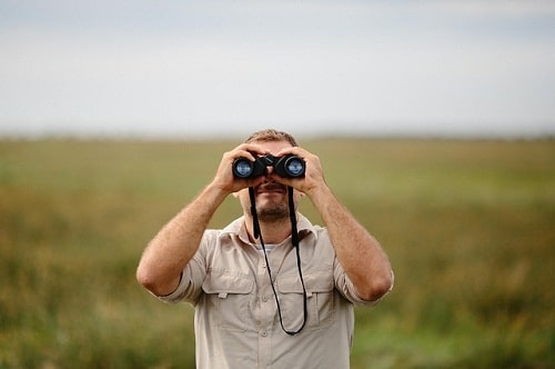 man using binocs in open field