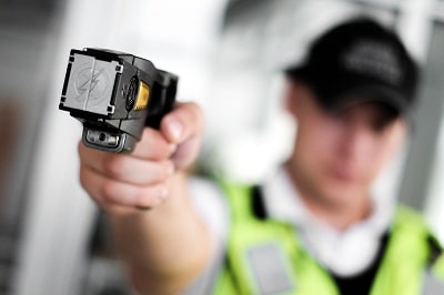 Closeup view of a loaded stun gun in a hand of a young man wearing high visibility vest