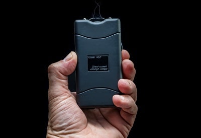 Hand holds a stun gun in front of black background