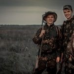 Hunters men with trophy in rural field