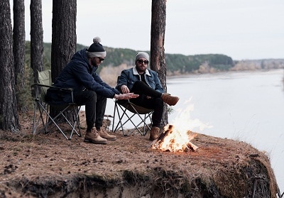 Male friends warming by fire on cliff