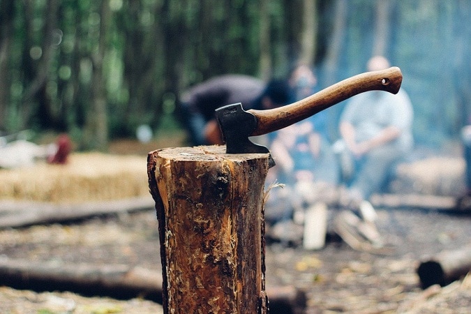 axe on chopped wood by the camp fire