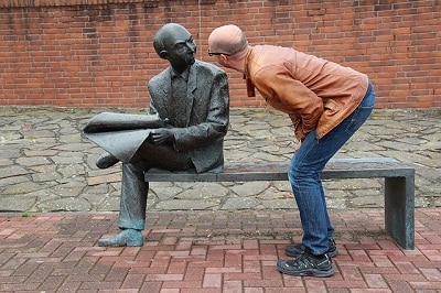 Bowed man looking at a sculpture