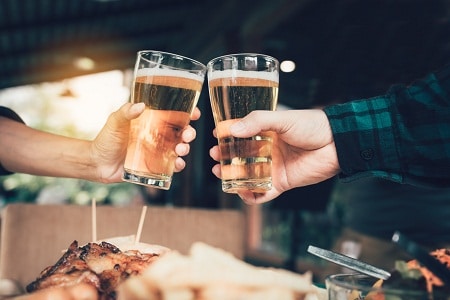 Two friends toasting and clinking with glass of beer