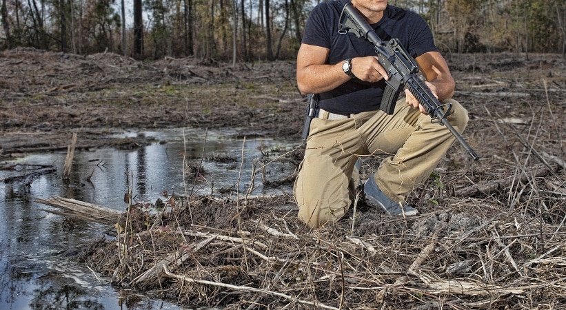 Man kneeling next to a water puddle with an AR-15