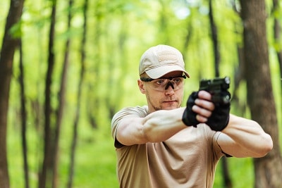 man aiming a handgun in the forest