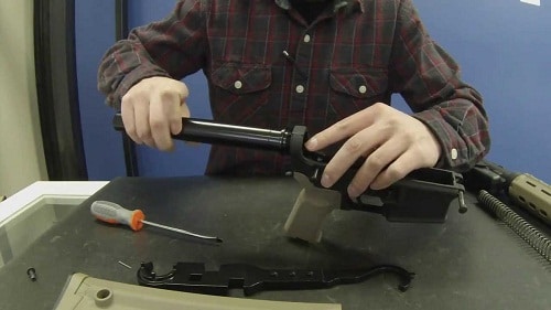 man assembling rifle with proper tools