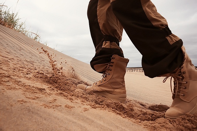 man walking on sand wearing military boots