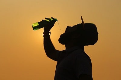 silhouette of man drinking from bottle
