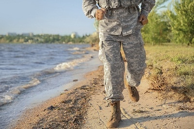 Running soldier in camouflage near river
