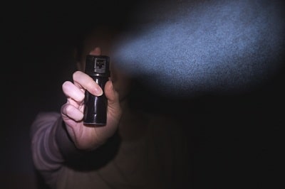 woman using pepper spray in black background