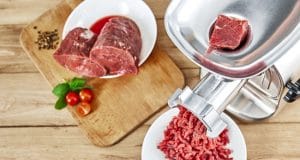 Fresh forcemeat cutting board with Meat grinder on kitchen table