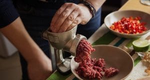 Mens hands making forcemeat with meat grinder