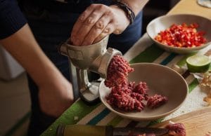 Mens hands making forcemeat with meat grinder