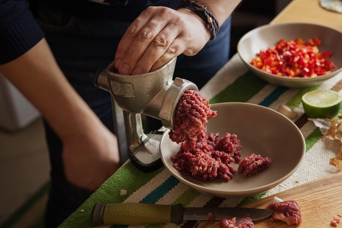 Men's hands making forcemeat with meat grinder