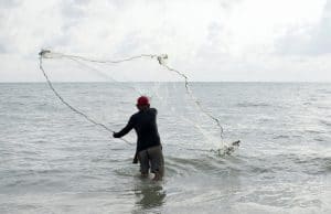 fisherman casting net in open water