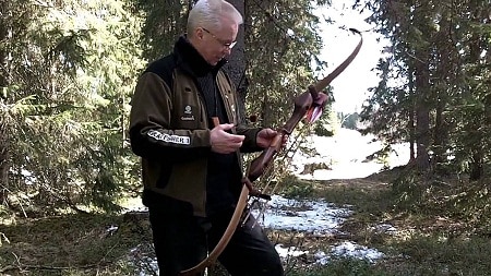 man holding recurve bow in the woods