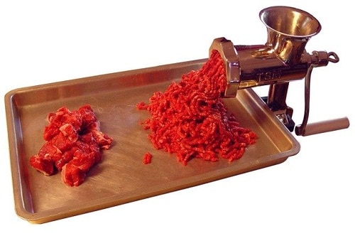 meat grinder with meat chunks and ground on tray