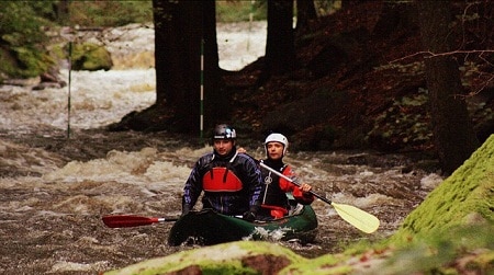 men white water rafting in canoe