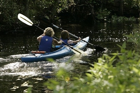 adult and kid paddling kayak on river