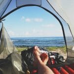 Backpackers legs stretched in tent with lake view