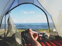 backpackers legs stretched in tent with lake view