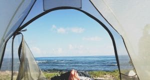backpacker's legs stretched in tent with lake view