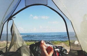 backpacker's legs stretched in tent with lake view