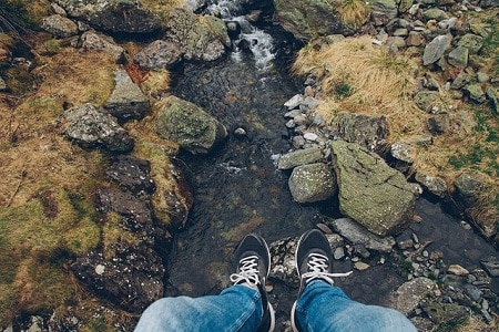 dangling legs above rocky stream