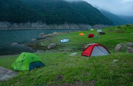 different tents on grassy land by the river
