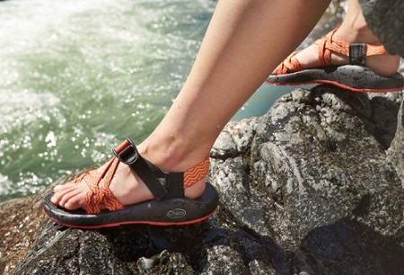 feet with water sandals stepping on a rock