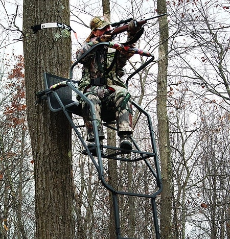 hunter aiming on a ladder treestand