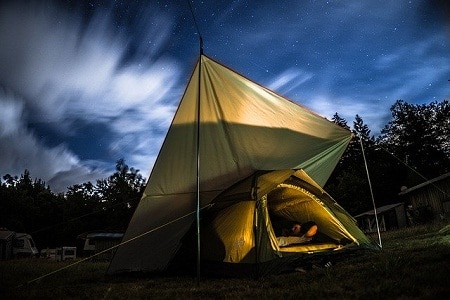 Man in tent under a cloudy night sky