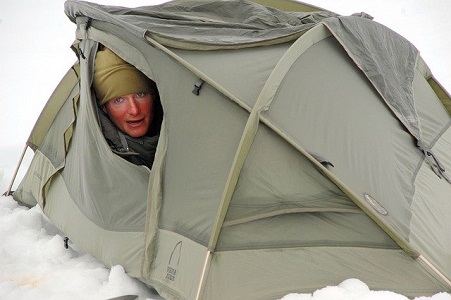 man picking through tent on snow