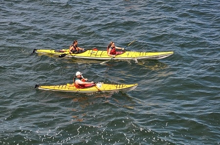 single and tandem kayak paddled side by side on open water