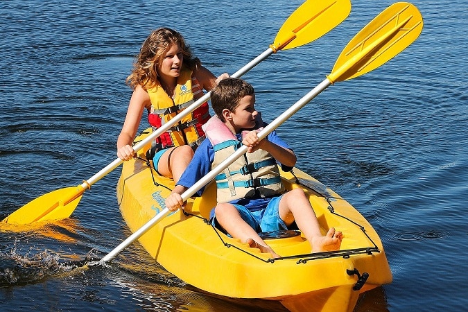 teens paddling kayak on a sunny day