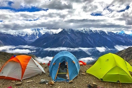 Three tents arranged on ground overlooking mountains