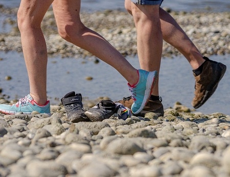 two pairs of legs walking on a rocky shore