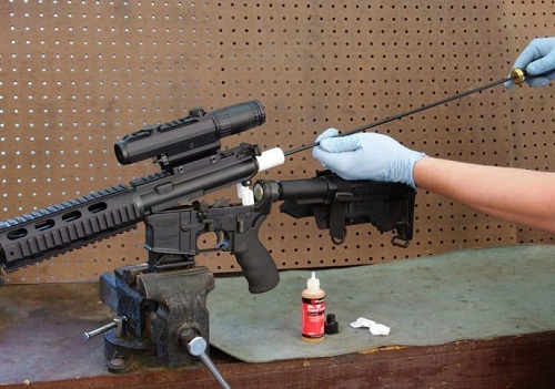 Gloved hands cleaning rifle on stand