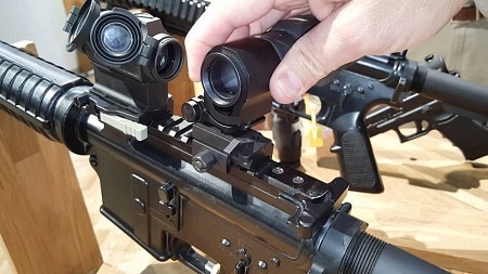 hand attaching magnifier to rifle