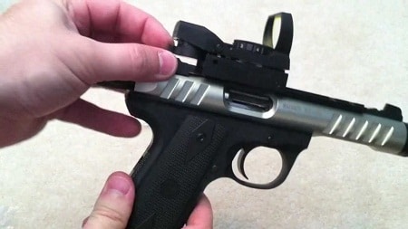 hand installing red dot sight on pistol