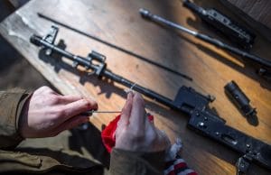 man cleaning disassembled rifle
