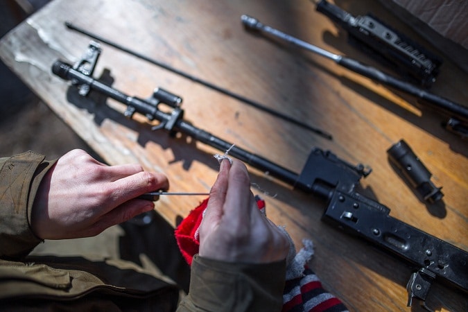 man cleaning disassembled rifle