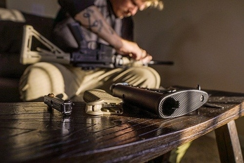 Man disassembling air rifle with some parts table