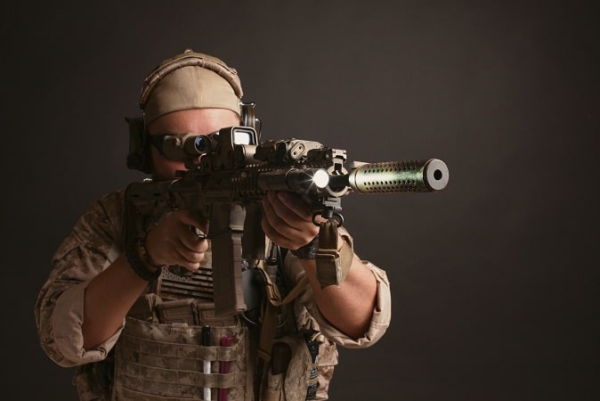 man in full gear aiming airsoft rifle using holographic sight