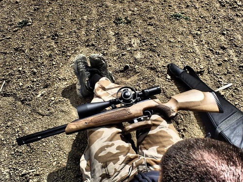 rifle on soldier's lap in open field